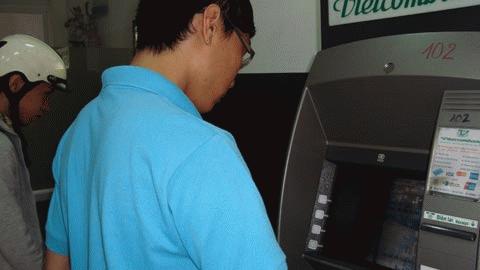 Khách hàng rút tiền tại máy  ATM vừa thao tác vừa hồi hộp vì sợ tiền rách. Ảnh: T.N