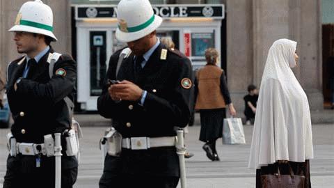 Một cảnh sát Italia đang mải mê với chiếc di động của mình trong lúc đi tuần trên đường phố Milan (Ảnh: Reuters)