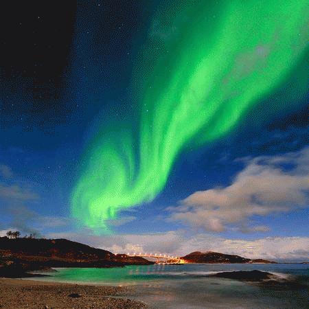 Một cực quang màu xanh tuyệt đẹp dường như uốn lượn như dòng sông bên trên đảo Troms của Na Uy. Cực quang được sinh ra do sự tương tác của các hạt mang điện tích từ gió mặt trời với tầng khí quyển bên trên của Trái đất. Các cực quang mạnh nhất thường diễn ra sau sự phun trào hàng loạt của Mặt trời. Các dải sáng này liên tục chuyển động và thay đổi làm cho chúng trông giống như những dải lụa màu trên bầu trời.  (Ảnh: Thilo Bubek)